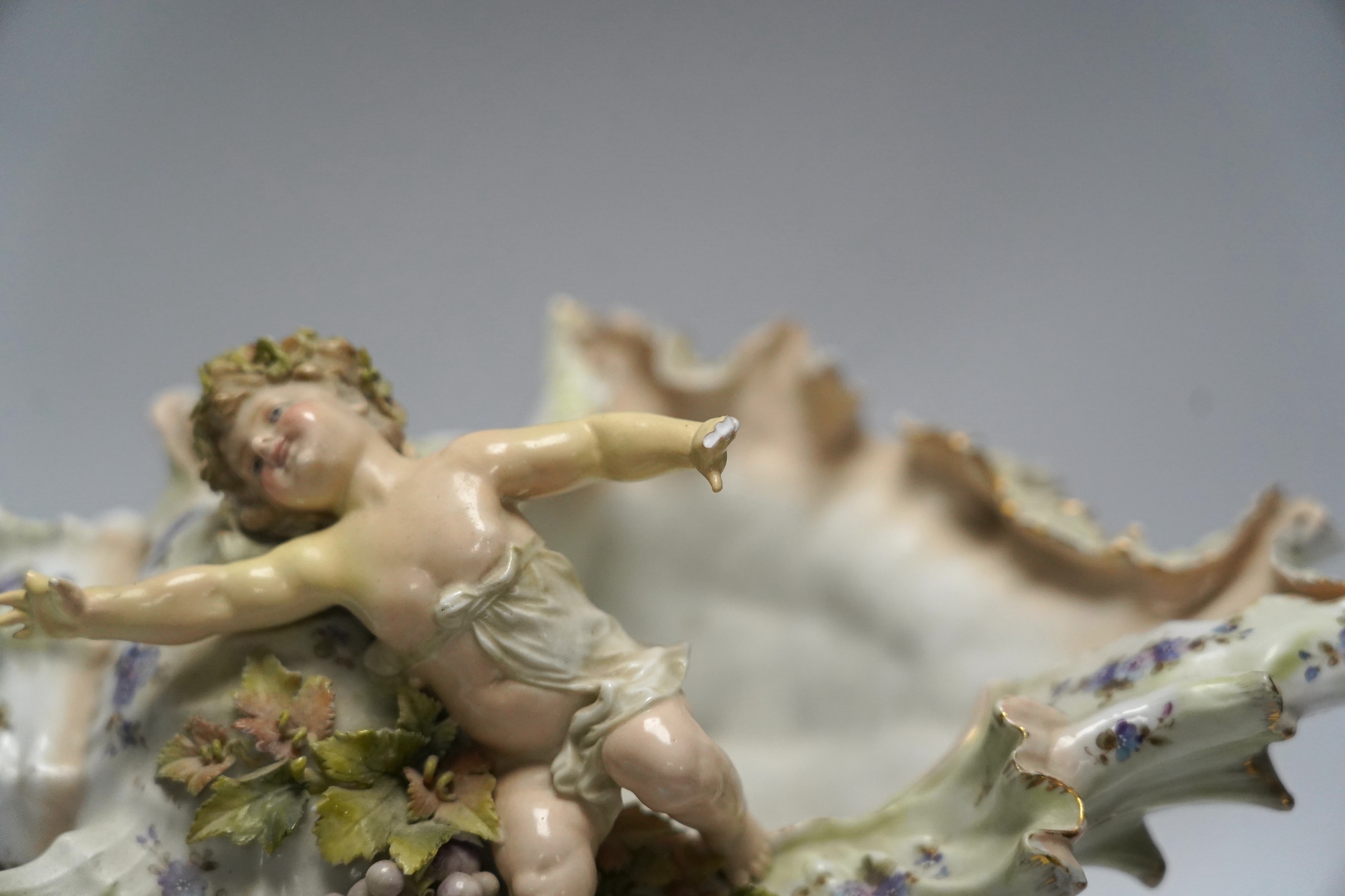 A porcelain shell-shaped centrepiece, a Dresden pill box, a pair of taper holders and a porcelain figure, tallest 21cm